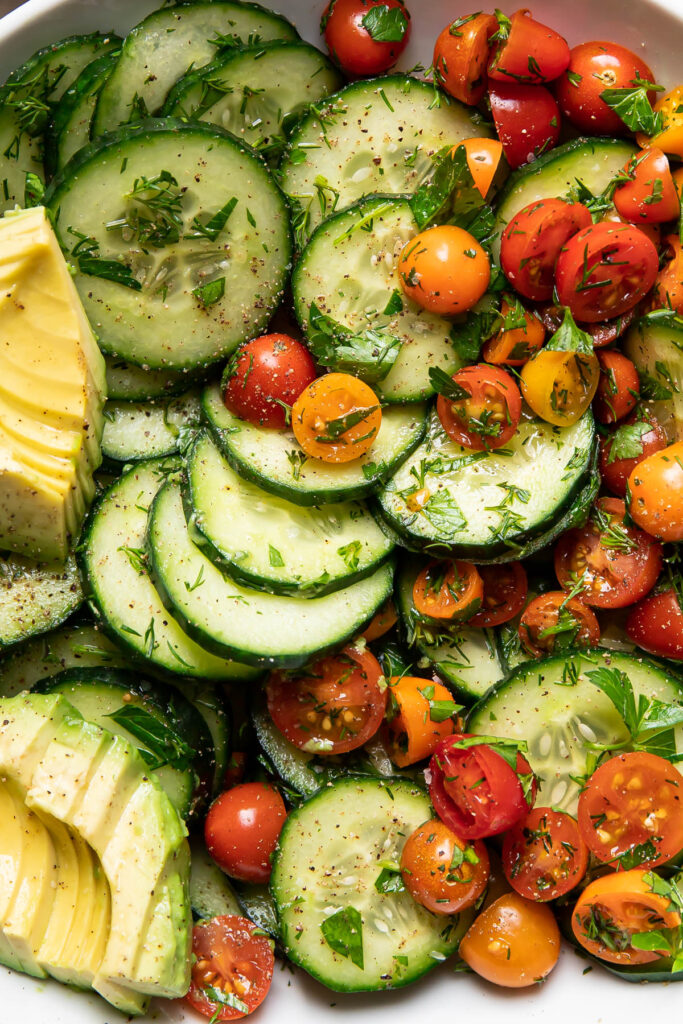 Up close image of a cucumber avocado salad with tomatoes.