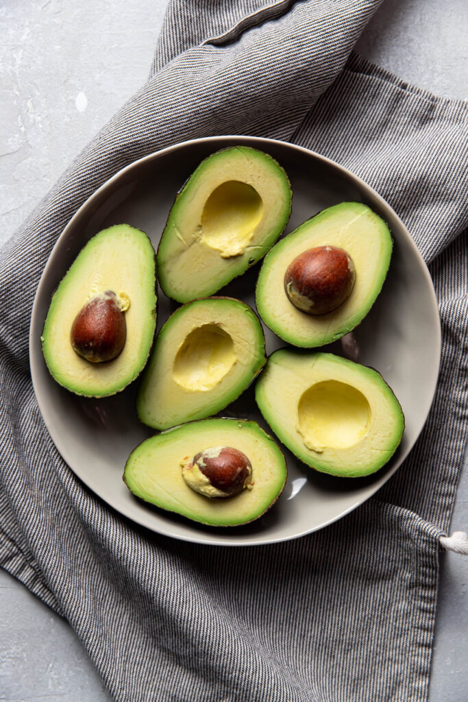 avocados cut in half in a bowl.