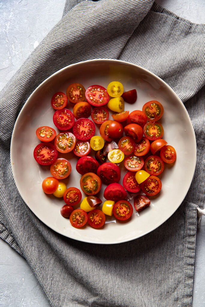 cherry tomatoes cut in a half in a bowl.