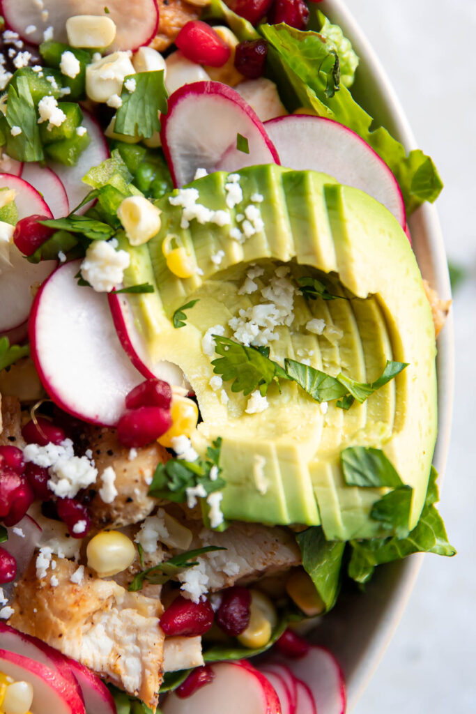 avocado pomegranate chicken salad in a bowl.