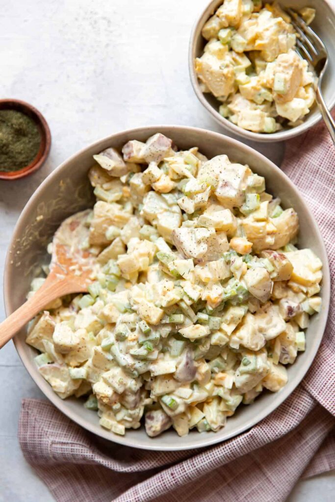 red potato salad with egg cucumber and celery in a bowl.