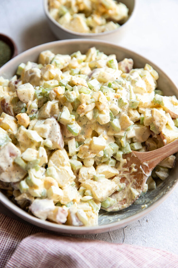 red potato salad with egg cucumber and celery in a bowl.