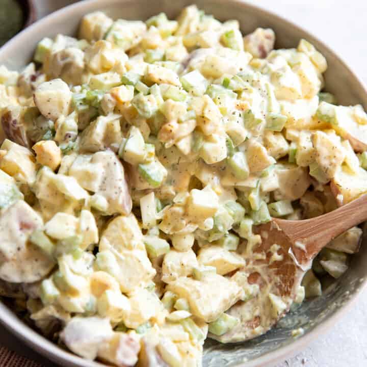 red potato salad with egg cucumber and celery in a bowl.