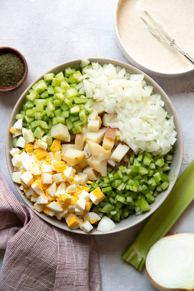 red potato salad with egg cucumber and celery in a bowl.