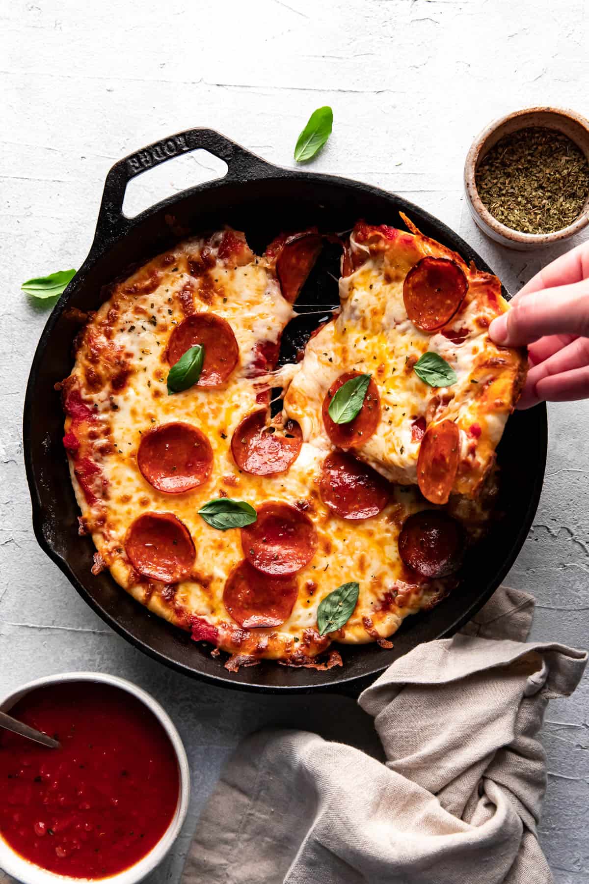 cast iron skillet pepperoni pizza with a piece being taken out of it.