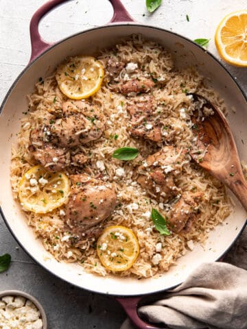 greek chicken and rice with lemon slices and feta in a pan.