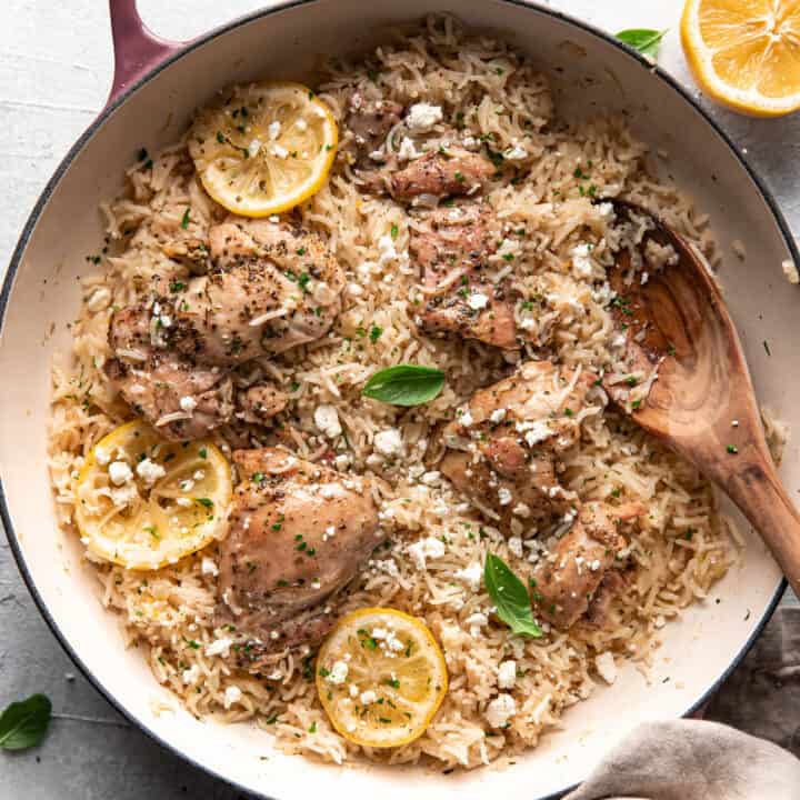 greek chicken and rice with lemon slices and feta in a pan.
