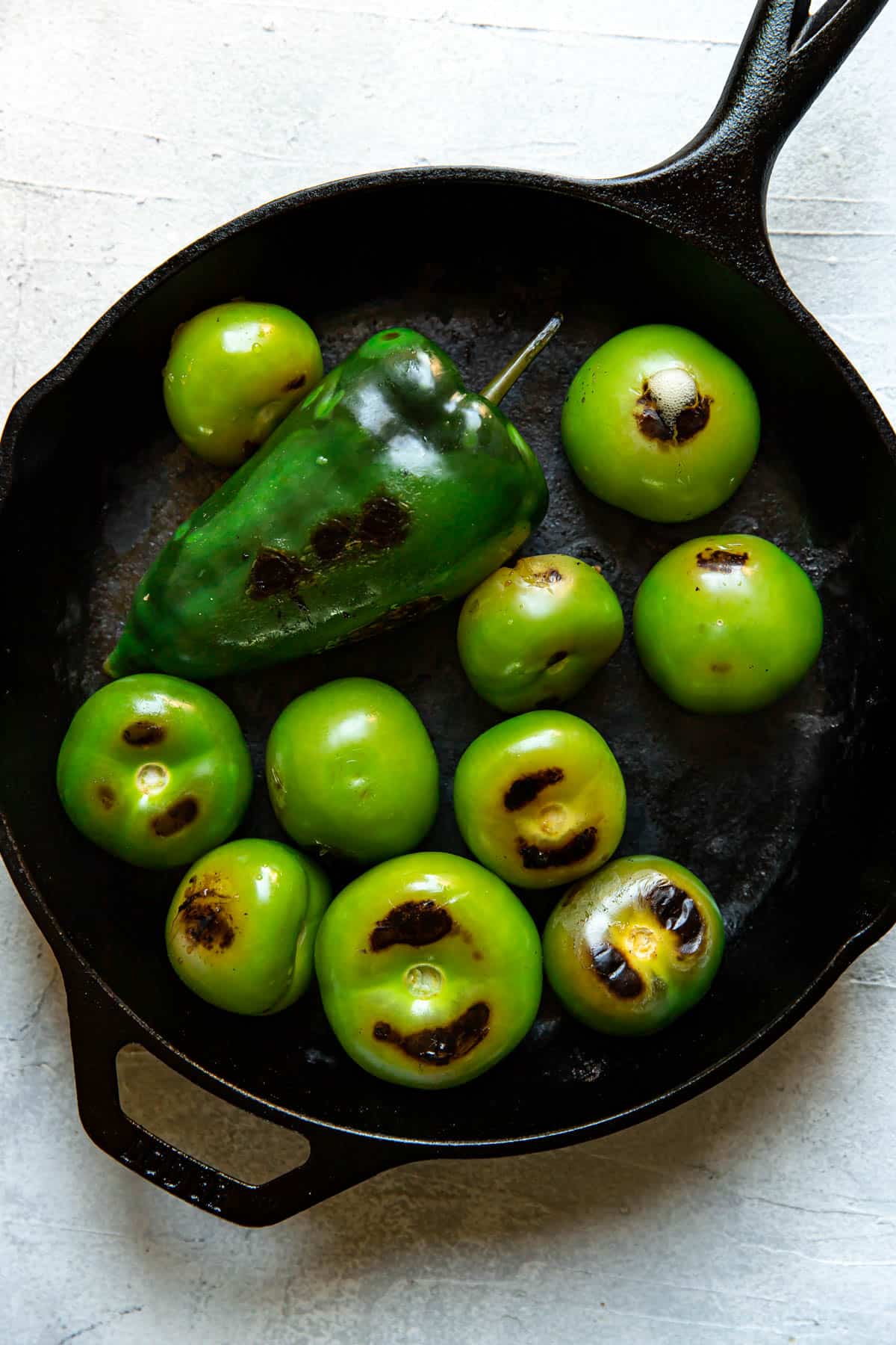 cooked tomatillos and poblano in a cast iron skillet.