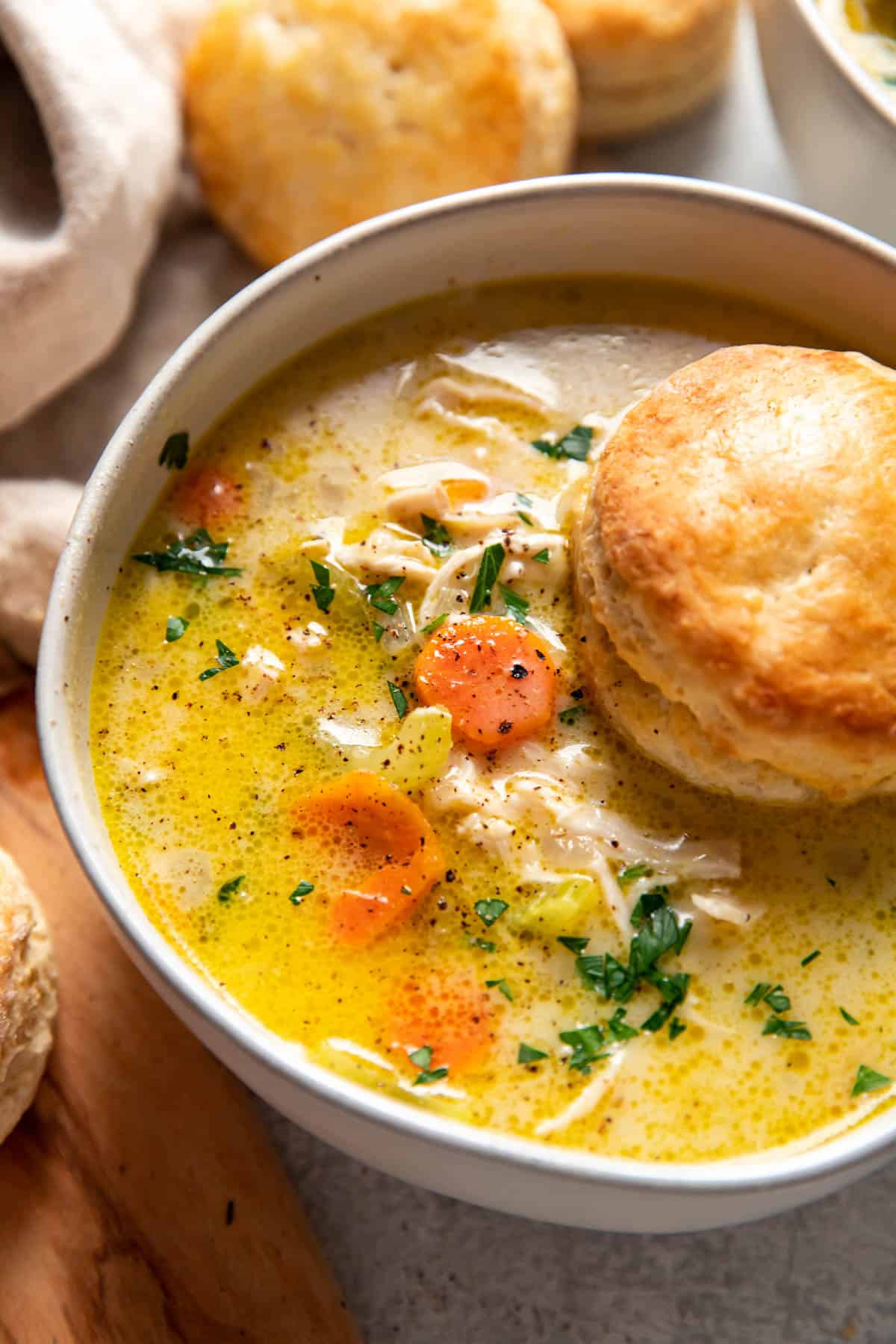 chicken pot pie soup with a biscuit on top in a bowl.