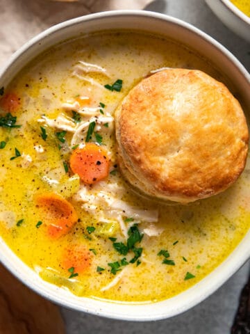 chicken pot pie soup with a biscuit on top in a bowl.
