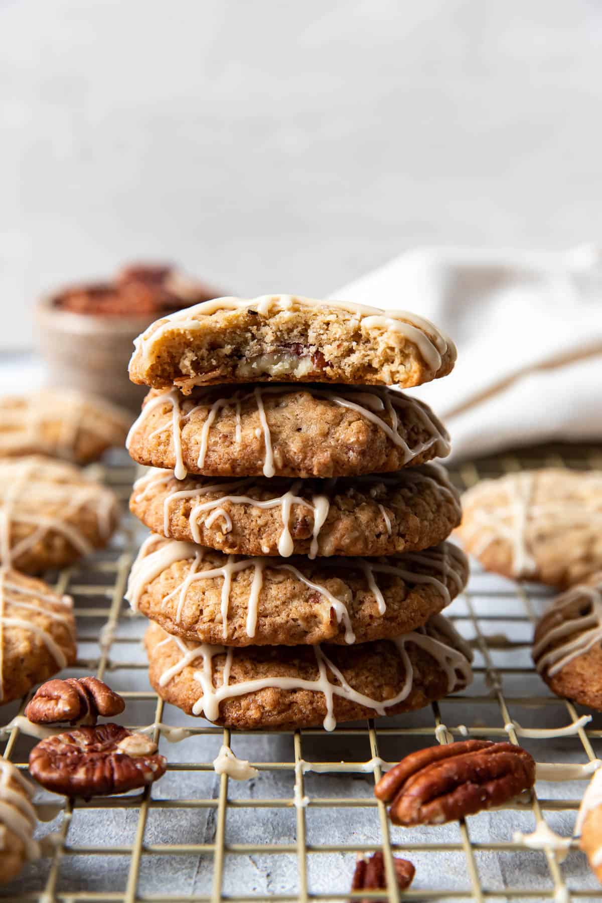 oatmeal pecan cookies with maple icing stacked on top of each other with a bite taken out.