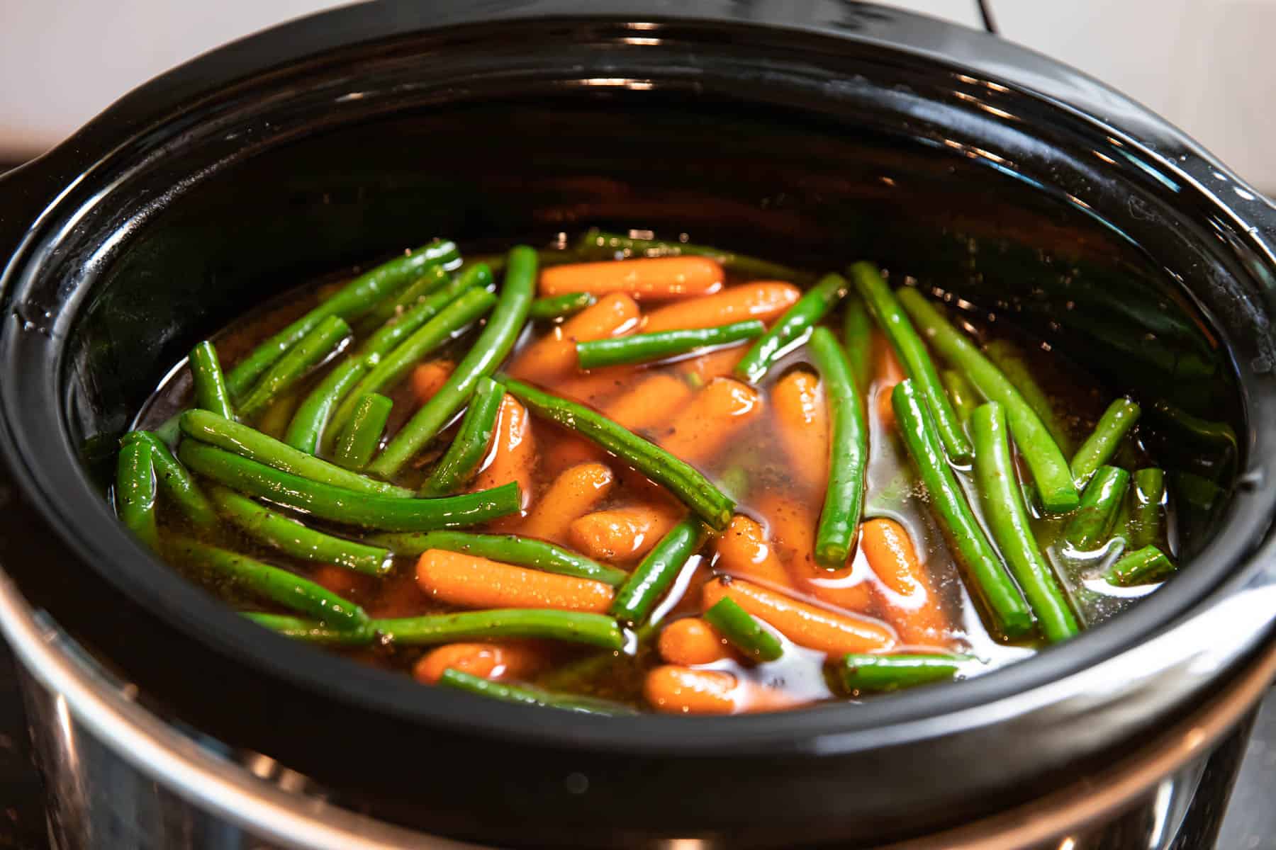 adding vegetables to a slow cooker for pot roast.