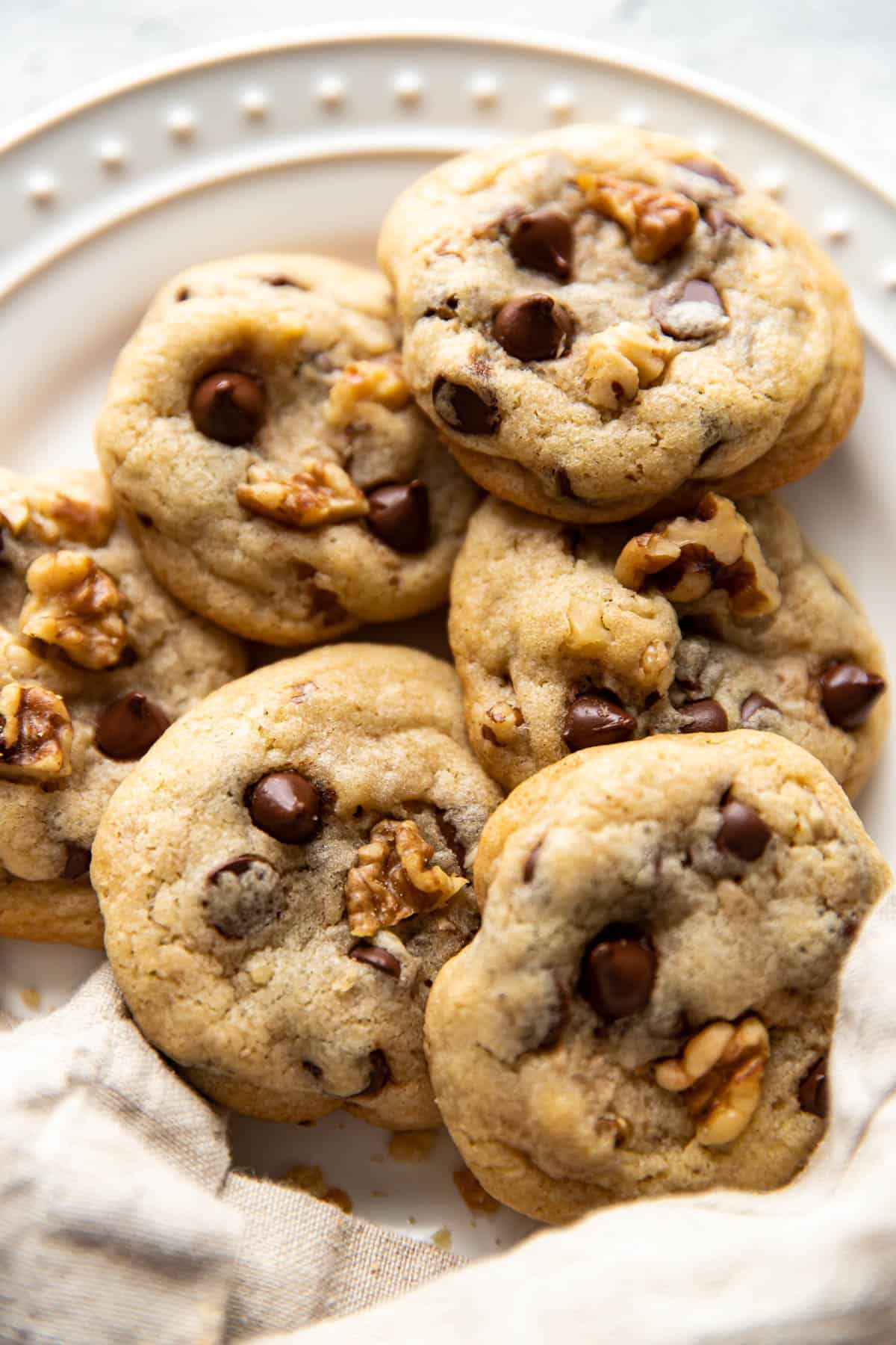 close up of walnut chocolate chip cookies on a plate.